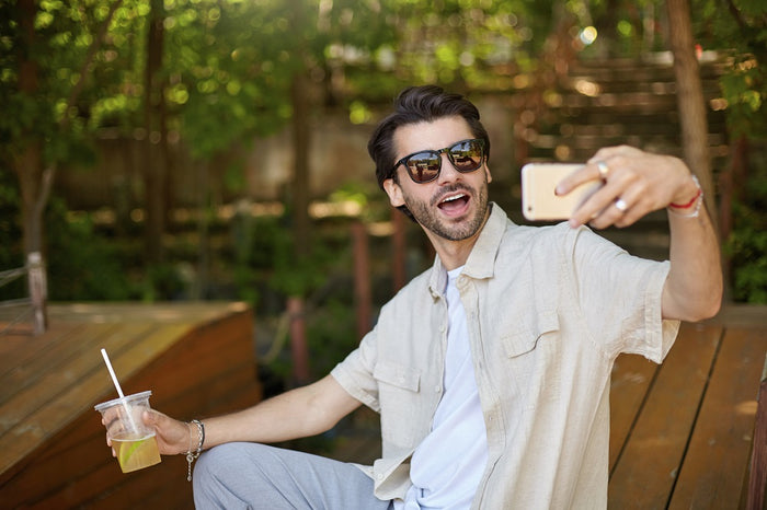Chico se toma un selfie. Lleva lentes de sol para hombre